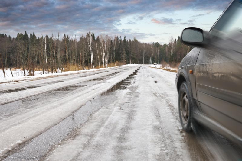 Bil som kör längst en snöig väg